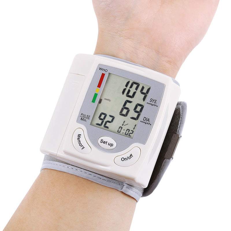 Wrist blood pressure monitor displaying readings on a person's wrist.