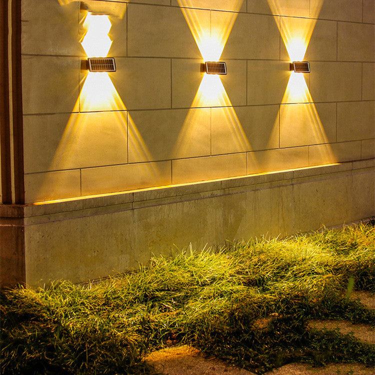 Solar outdoor wall lights illuminating a stone wall with warm light.