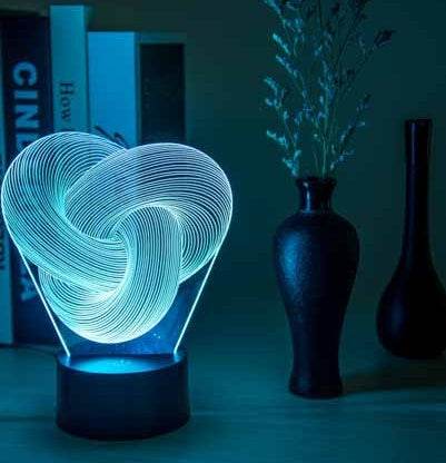 Twist Abstract LED 3D night light on a table with decorative vases, emitting a soft glow.