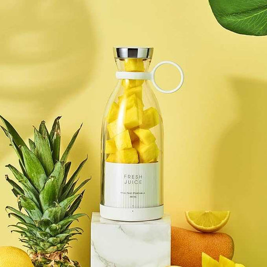 Portable Blendy Bottle blender with pink design next to a glass of juice, grapefruit, berries, and a palm leaf.