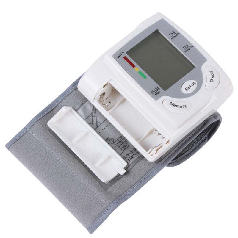 Wrist blood pressure monitor displaying readings on a person's wrist.