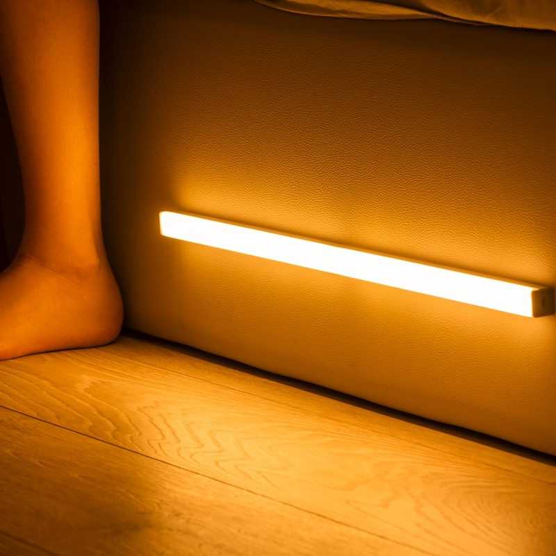LED sensor light bar emitting warm light under a sofa.