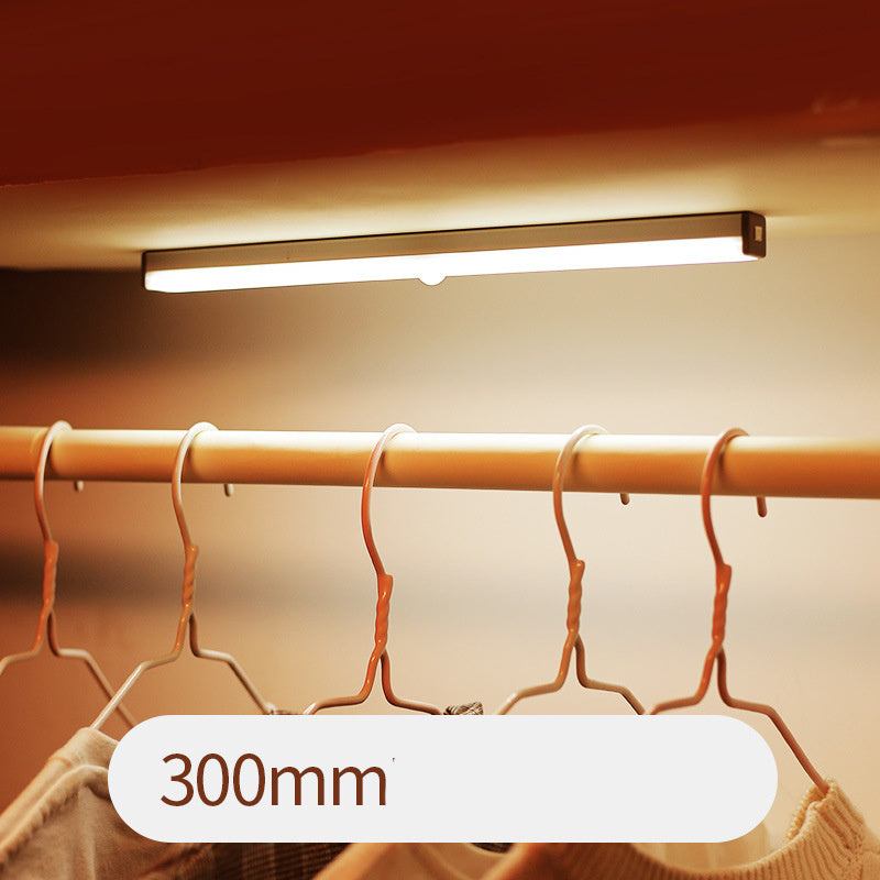 LED sensor light bar emitting warm light under a sofa.