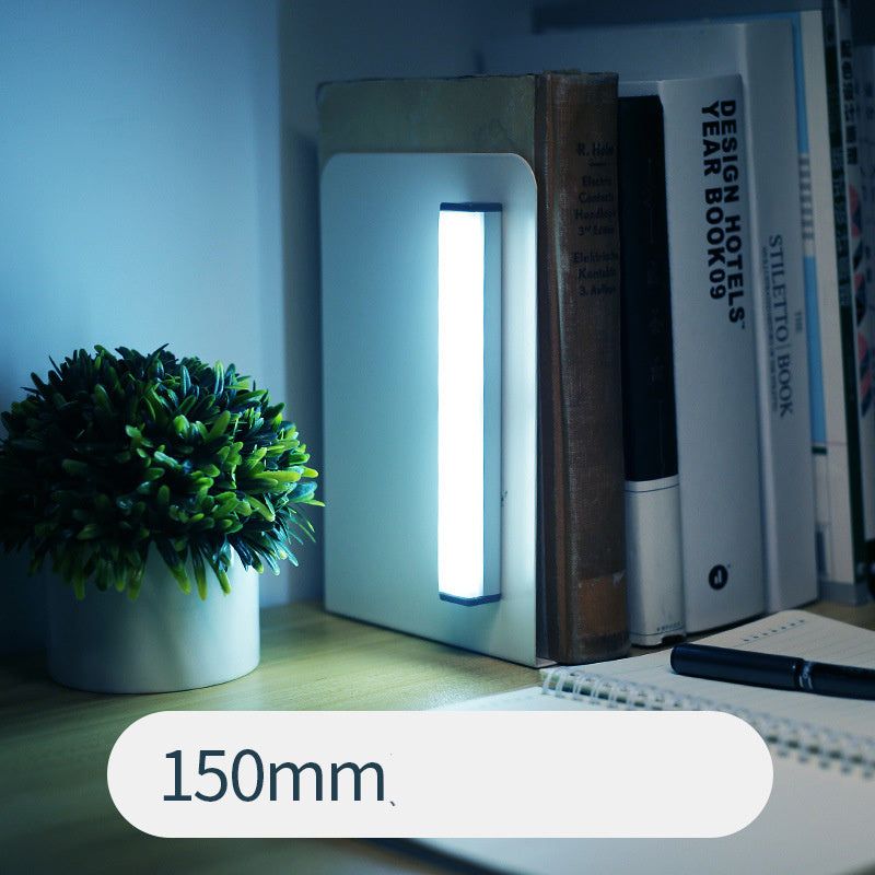 LED sensor light bar emitting warm light under a sofa.
