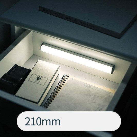 LED sensor light bar emitting warm light under a sofa.