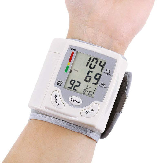 Wrist blood pressure monitor displaying readings on a person's wrist.
