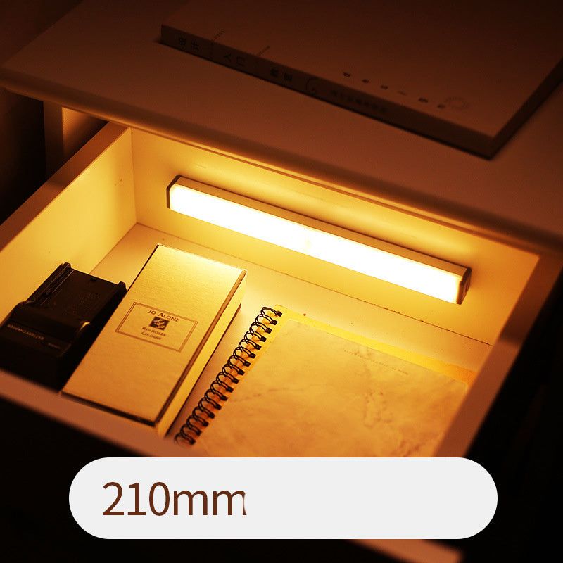 LED sensor light bar emitting warm light under a sofa.