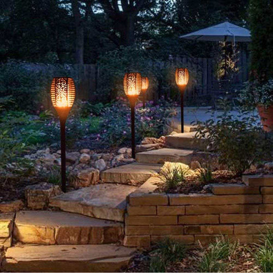 Outdoor pathway illuminated by LED waterproof solar torch lights with warm, flickering glow.
