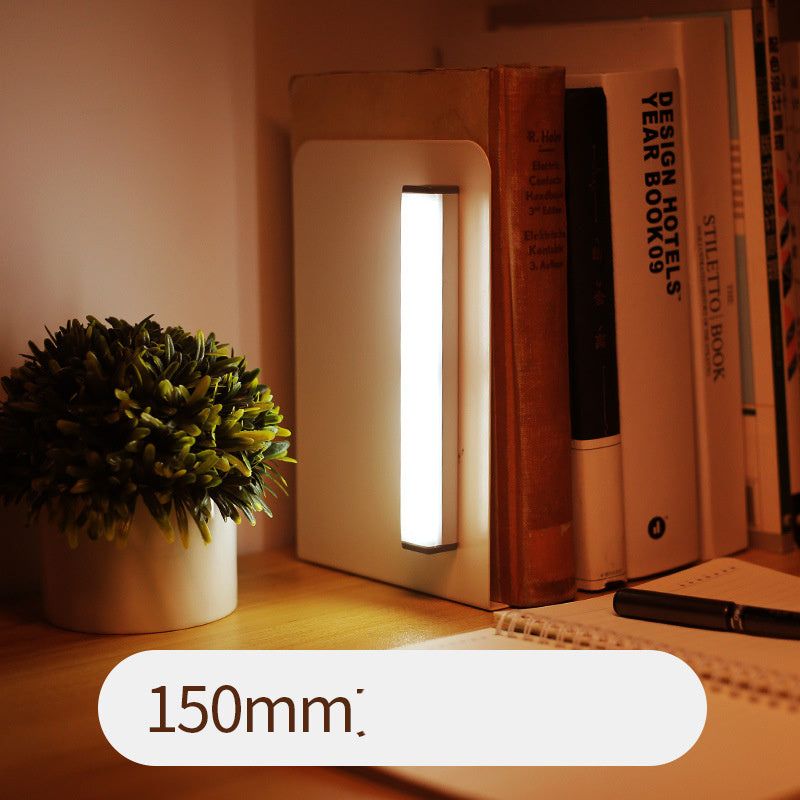LED sensor light bar emitting warm light under a sofa.
