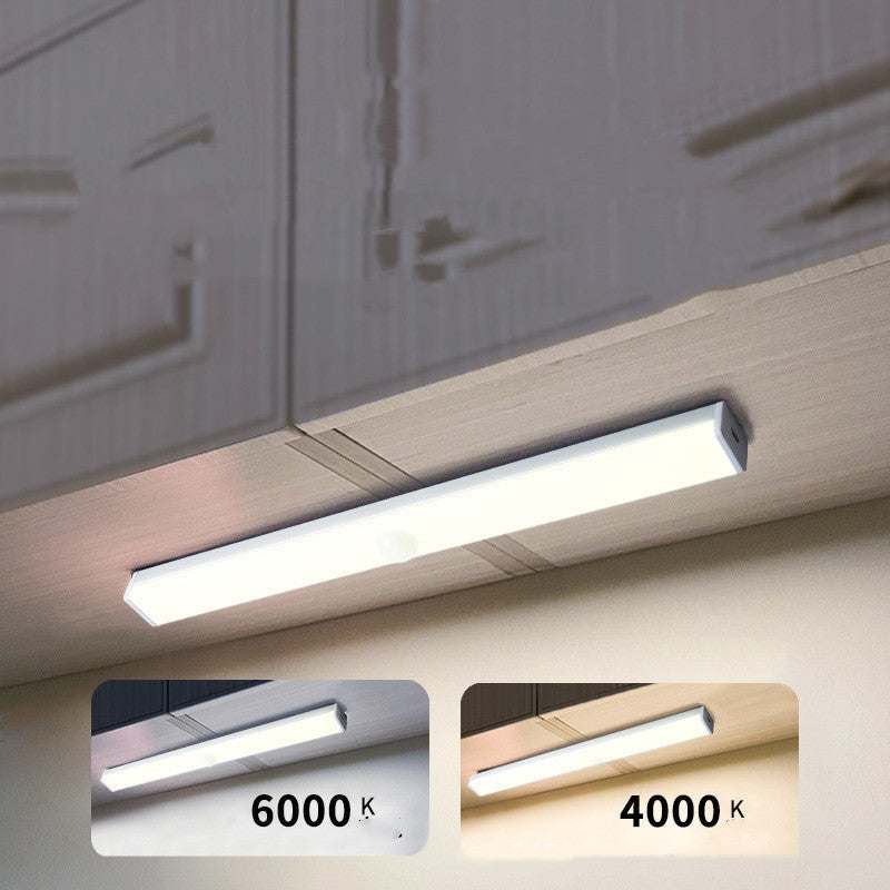 LED sensor light bar emitting warm light under a sofa.