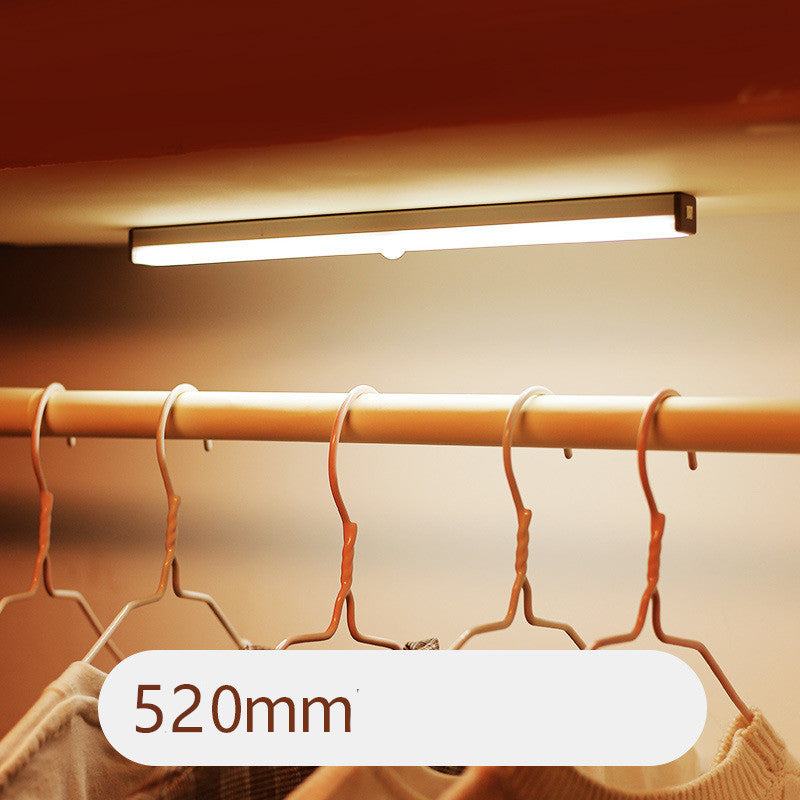 LED sensor light bar emitting warm light under a sofa.