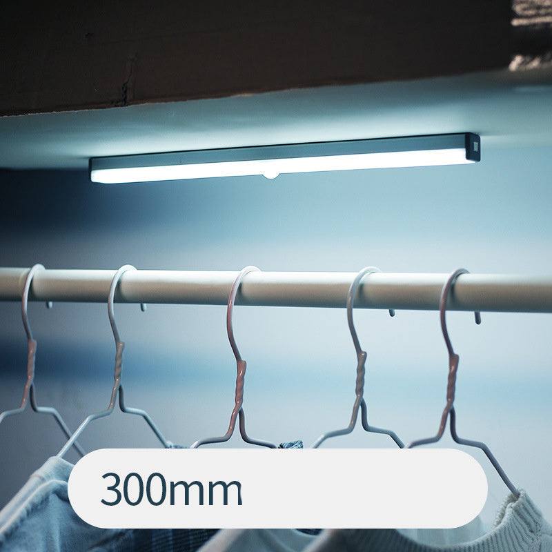 LED sensor light bar emitting warm light under a sofa.