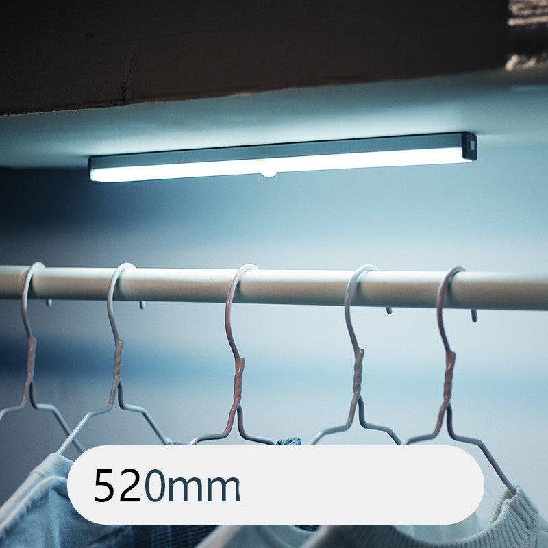 LED sensor light bar emitting warm light under a sofa.